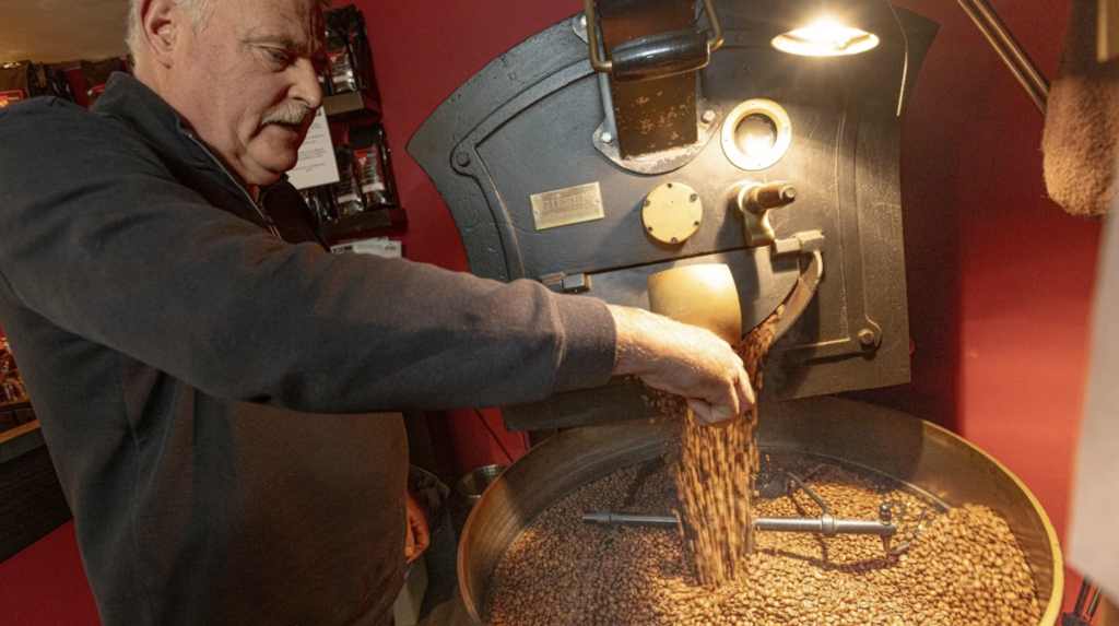 Ein Kaffeebohnen-Experte prüft mit einer Kaffeebohnen-Schaufel die Qualität der gerösteten Kaffeebohnen während der Röstung